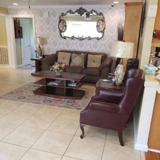 A cozy living room with a sofa, armchair, and a coffee table, complemented by decorative elements like a mirror and lamps.
