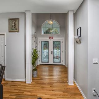 A brightly lit home entrance with wood flooring and a potted plant.