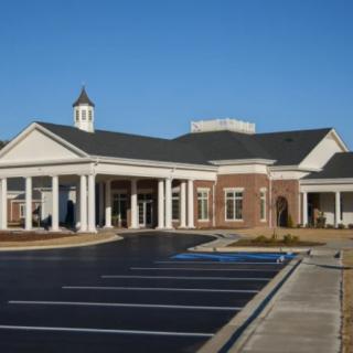 A well-maintained building with a parking lot in the foreground under a clear blue sky.