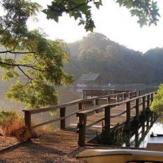 A tranquil pier extending over a calm lake surrounded by mountains and lush trees.