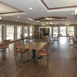 A spacious dining area with wooden floors, large windows, and multiple tables and chairs.