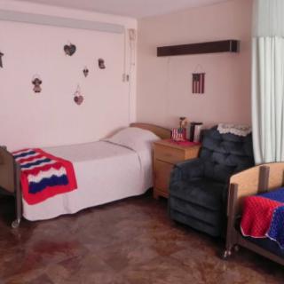 A cozy bedroom featuring a single bed, colorful blankets, and decorative wall hangings.