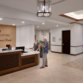 A warm and inviting reception area with a modern design, featuring a front desk and visitors engaging with staff.