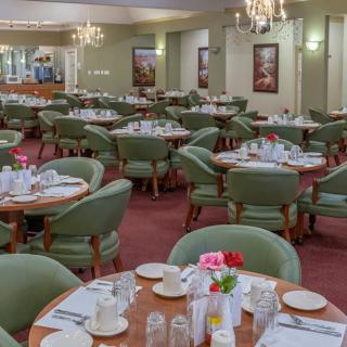 A spacious dining area with elegantly set tables and chandeliers.