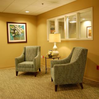 A cozy waiting room with two armchairs, a small table, and warm lighting.