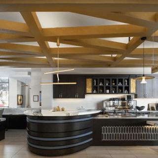 A modern restaurant interior featuring a sleek bar counter, wooden ceiling design, and stylish lighting fixtures.