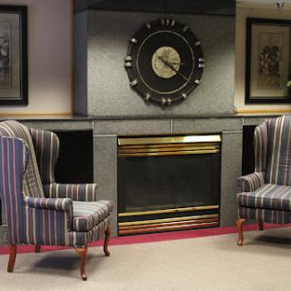 A cozy living room setup featuring striped armchairs and a decorative fireplace.