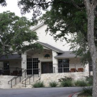 A view of a building entrance surrounded by trees and landscaping.
