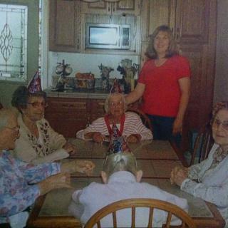 A family gathering in the kitchen, celebrating with party hats and seated around a table.
