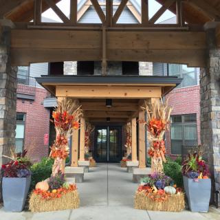 A beautifully decorated entrance with autumn-themed decor including pumpkins and cornstalks.