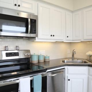 A modern kitchen with white cabinets and stainless steel appliances.