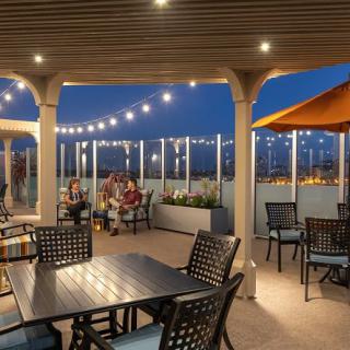 A cozy outdoor patio with string lights illuminating the evening ambiance, featuring tables and chairs for relaxation.