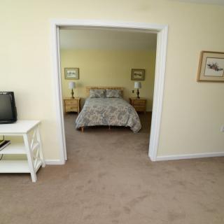 A cozy bedroom with a double bed, nightstands, and a small TV in an adjacent room.
