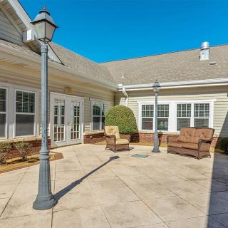 A sunny outdoor patio area with seating and lamp posts surrounded by building walls.