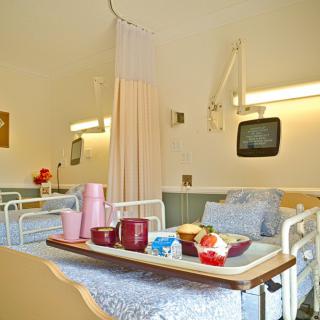 A hospital room with a patient bed and a meal tray.