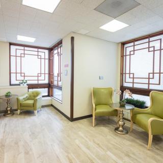 A modern and bright waiting room featuring stylish green chairs and large windows.