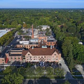 Aerial view of a brick building complex surrounded by trees and a parking lot.