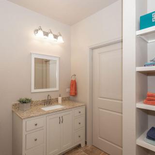 A neatly organized bathroom with a vanity, sink, and towel storage.