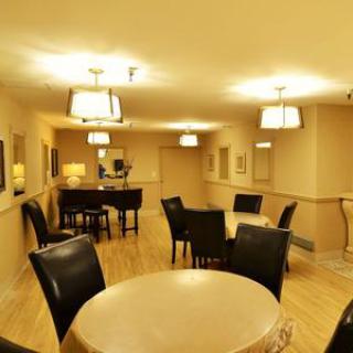 A cozy lounge area featuring tables and chairs, illuminated by warm lighting.