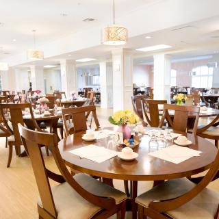 A spacious and elegantly decorated dining area with wooden tables and chairs, beautifully set for guests.