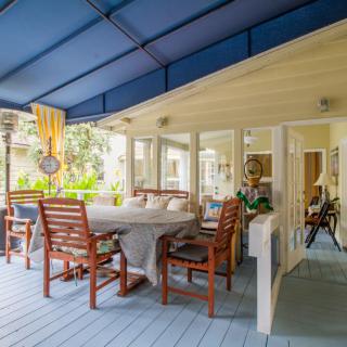 A cozy outdoor patio with a dining area featuring wooden furniture and a blue canopy.