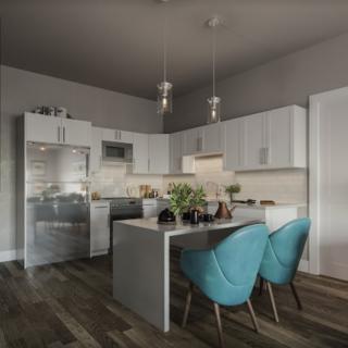 A modern kitchen with a central island, pendant lights, and blue chairs.