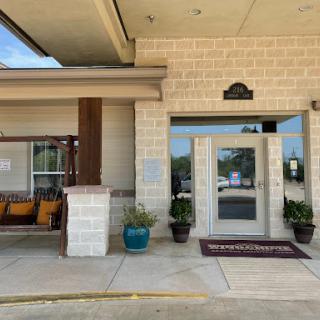 A welcoming entrance to a hotel featuring a swing and potted plants.