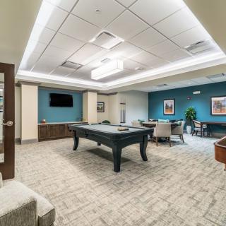 A modern game room featuring a pool table, seating area, and a wall-mounted television.