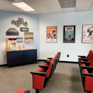 A cozy waiting room featuring red chairs and movie-themed decor, perfect for cinema enthusiasts.