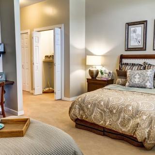 A cozy and elegantly decorated bedroom with a bed, nightstand, lamp, and framed artwork.