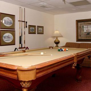 A cozy game room featuring a classic billiards table, surrounded by artwork and ambient lighting.