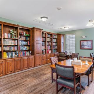 A cozy library room with wooden bookshelves and a table for reading.