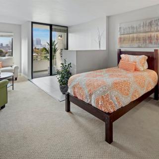 A modern bedroom with a single bed and balcony offering a city view.