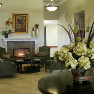 A cozy living room featuring a fireplace, elegant furniture, and decorative flowers.