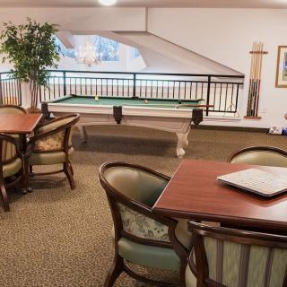 A cozy game room featuring a pool table and a seating area with tables and chairs.