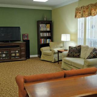 A cozy living room with a television, bookshelf, and comfortable seating.