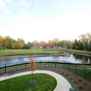 A serene landscape featuring a pond surrounded by lush greenery and a winding pathway.