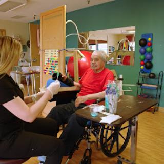 A therapist assists an elderly patient in a rehabilitation session.