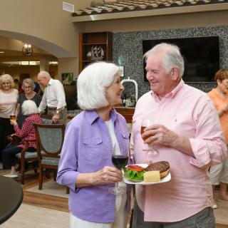 Elderly couple enjoying a social gathering with food and drinks.