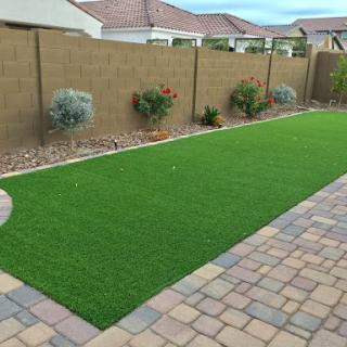 A well-maintained backyard featuring artificial grass and a paved patio.