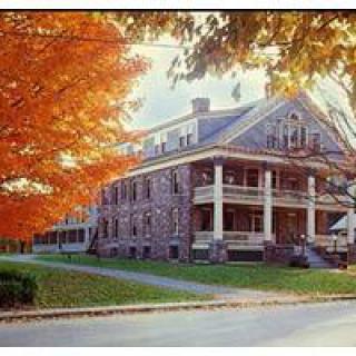 A historical brick building surrounded by vibrant autumn foliage.