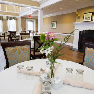 A cozy dining room with elegantly set tables and a fireplace.