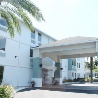 The entrance of a modern hotel with palm trees and an inviting facade.