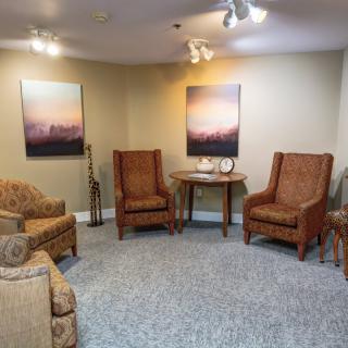 A cozy living room setup with multiple chairs, a small table, and artwork on the walls.