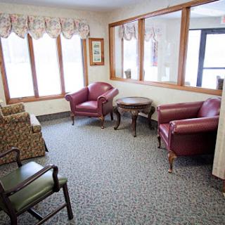A cozy seating area featuring comfortable chairs and a small table, illuminated by natural light from the windows.