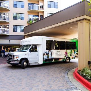A shuttle bus parked under a building entrance.