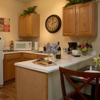 A cozy kitchen with wooden cabinets, white countertops, and various appliances including a microwave and coffee maker.