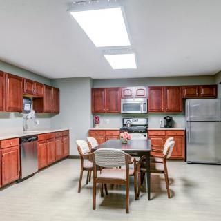 A modern kitchen with wooden cabinets, stainless steel appliances, and a dining table with chairs.