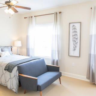 A bright and modern bedroom with a cozy bed, stylish sofa, and ample natural light.