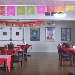 A decorated restaurant interior with tables and chairs, featuring colorful banners.